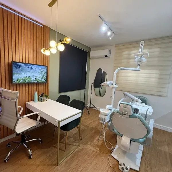Consultório da Humanized, com cadeira odontológica, parede ripada de madeira e televisão