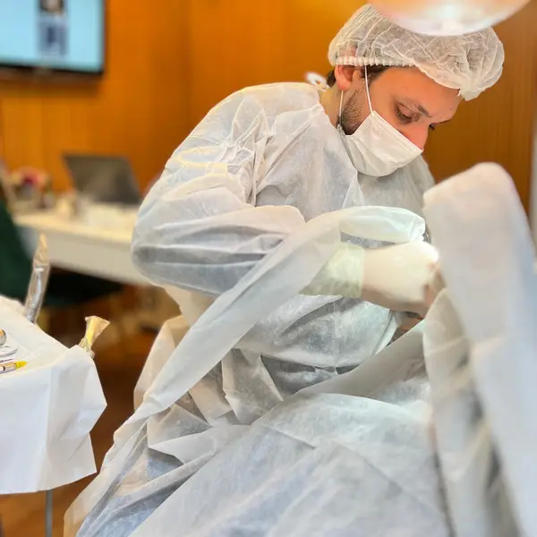 Cirurgiao-dentista paramentado realizando procedimento cirurgico sob o refletor na sala de cirurgia da clinica