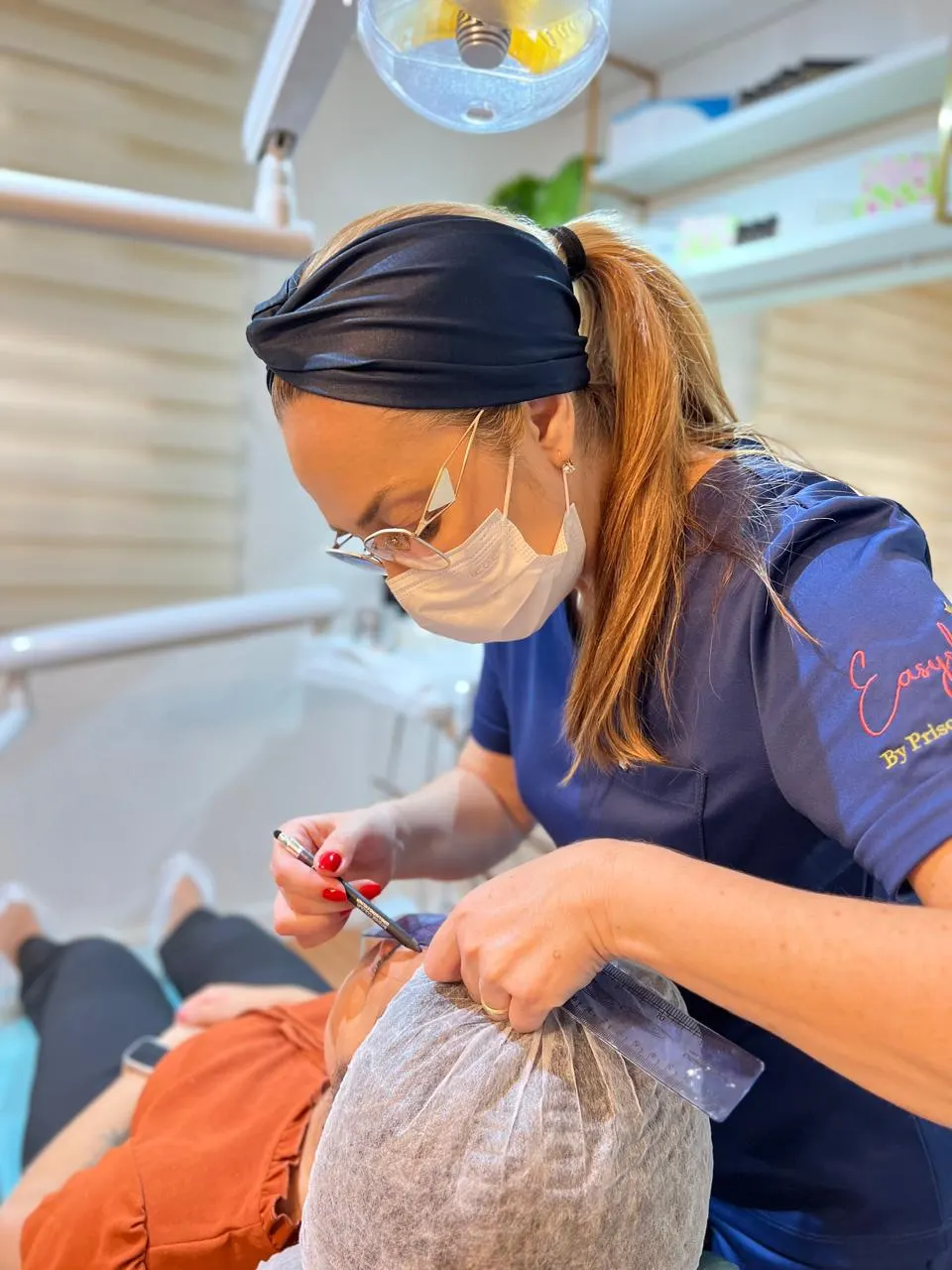 Dentista da Humanized demarcando o rosto de uma paciente com régua e lápis, antes do procedimento