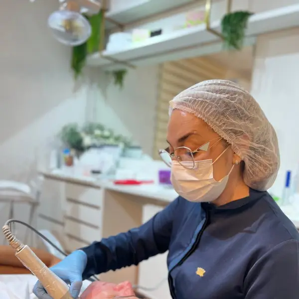 Profissional paramentada realizando procedimento facial em paciente deitado na maca da clinica