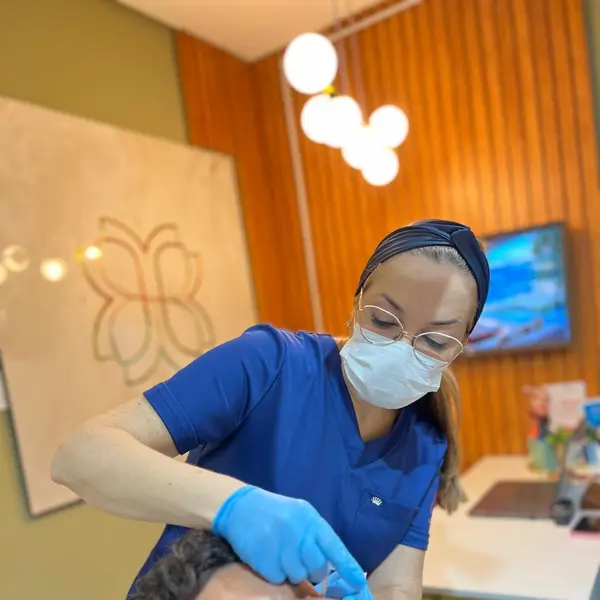 Profissional aplicando procedimento injetavel no rosto de paciente na clinica