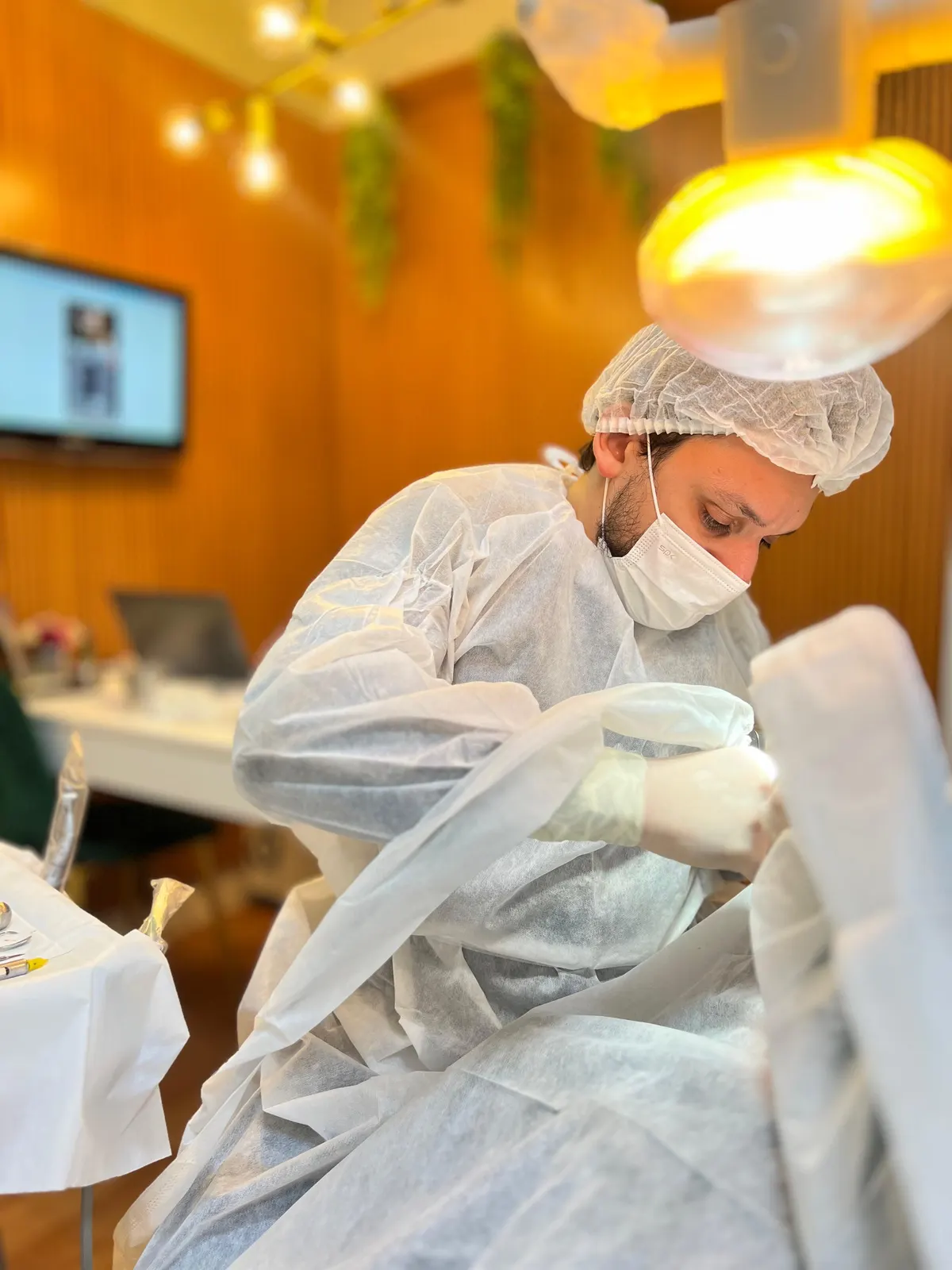 Cirurgião da Humanized, paramentado com touca, máscara e avental, concentrado durante um procedimento sob o refletor